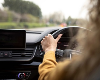 A woman in a yellow jumper driving a car