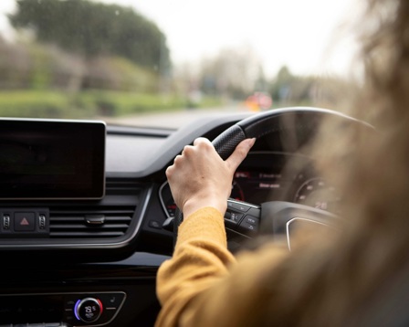 A woman in a yellow jumper driving a car