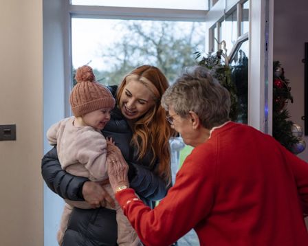 Family being greeted as they enter the front door