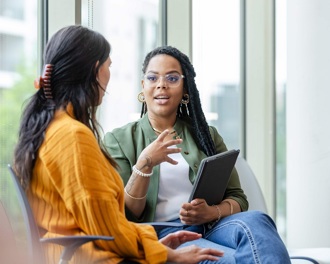 Two professional ladies sit in a medical environment chatting