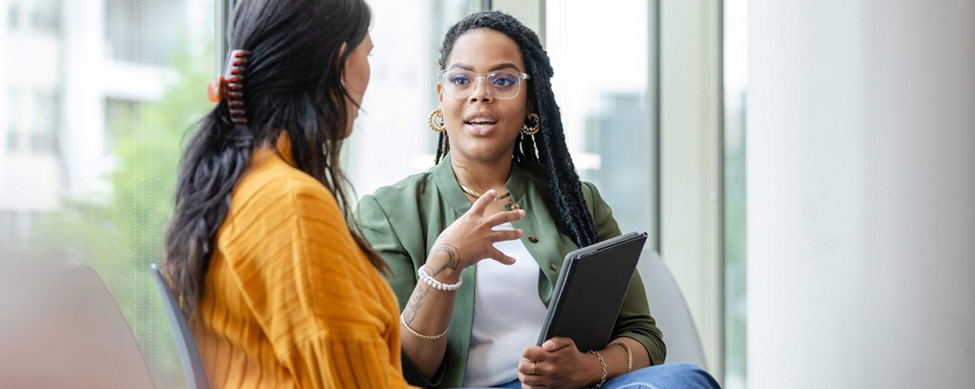 Two professional ladies sit in a medical environment chatting