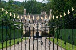 driveway-to-large-historic-manor-house-through-ornate-gates.jpg