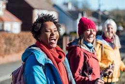 Three women smile as they stand outside on a sunny winter day