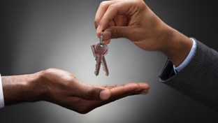 A close-up of one person handing over a set of keys to another, symbolizing property transfer or new ownership.