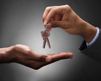 A close-up of one person handing over a set of keys to another, symbolizing property transfer or new ownership.