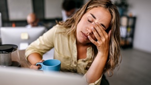 Woman at desk with her hand to her face