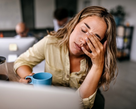 Woman at desk with her hand to her face