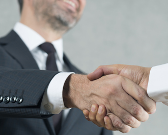 A professional handshake between two individuals, symbolizing agreement, partnership, or a successful deal.