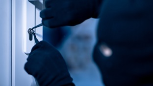 Gloved hands picking a front door lock