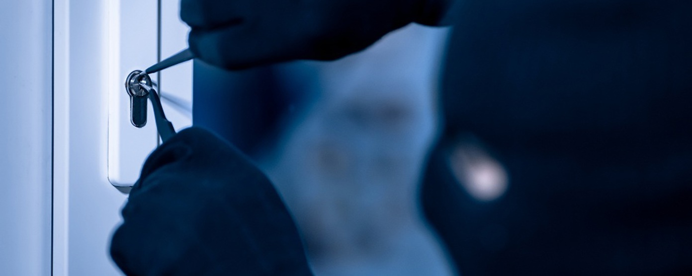 Gloved hands picking a front door lock