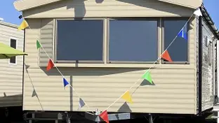 Beige static caravan decorated with colorful bunting across the front