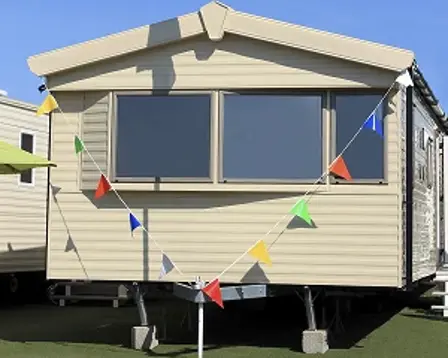 Beige static caravan decorated with colorful bunting across the front