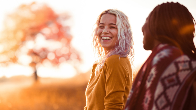 Two female friends smiling as as they talk outside