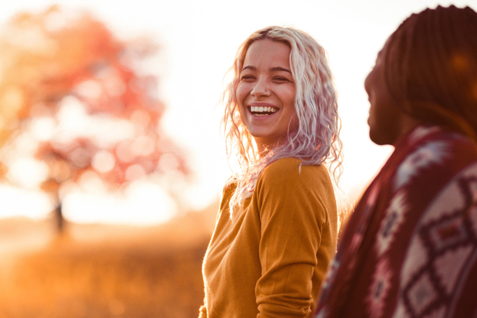 Two female friends smiling as as they talk outside