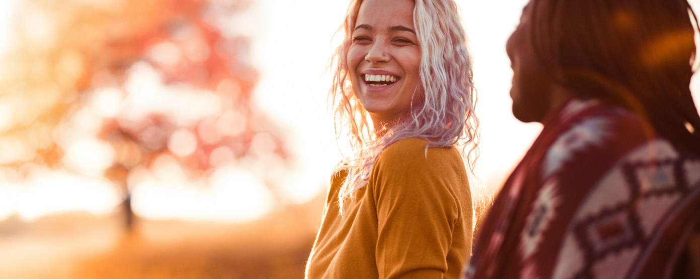 Two female friends smiling as as they talk outside