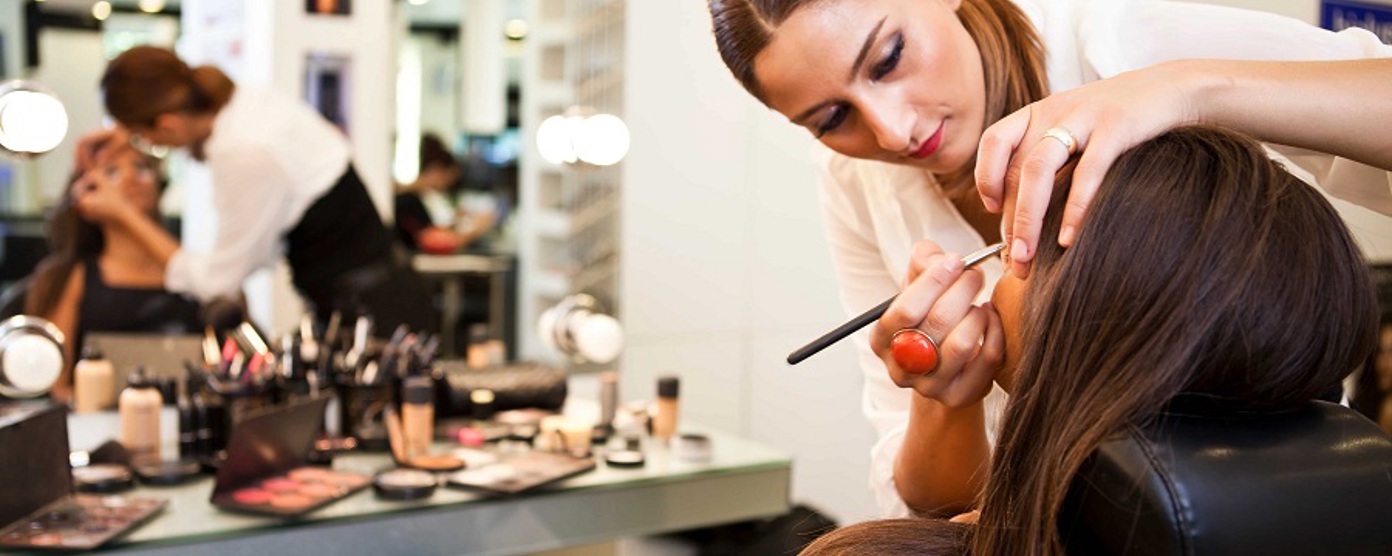 A female makeup artist applying makeup to a brunette in a chair