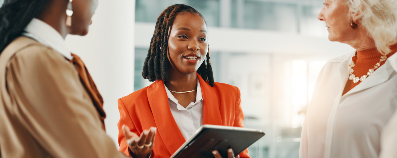 Three business woman in discussion, one holding a tablet