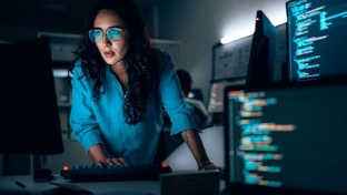 Professional woman in a shirt studying computer monitors