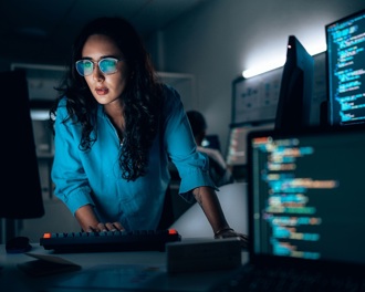 Professional woman in a shirt studying computer monitors