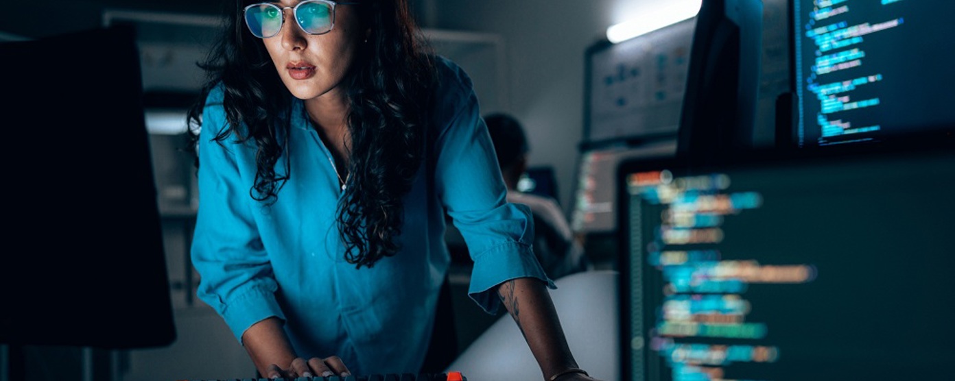 Professional woman in a shirt studying computer monitors