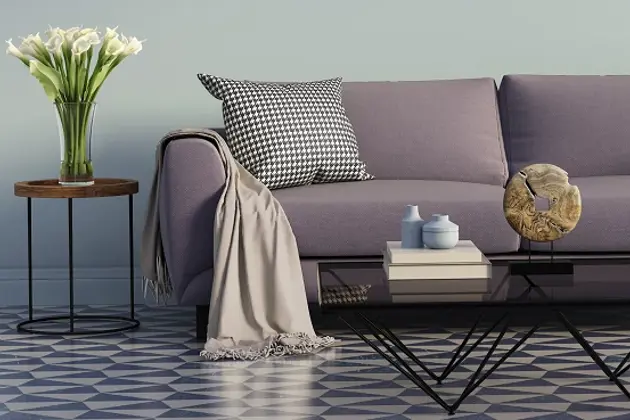 A stylish modern living room with a purple sofa, a patterned cushion, and a soft throw.
