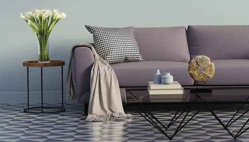 A stylish modern living room with a purple sofa, a patterned cushion, and a soft throw.