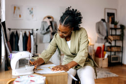 Young well dressed woman designing clothes at her small tailor workshop