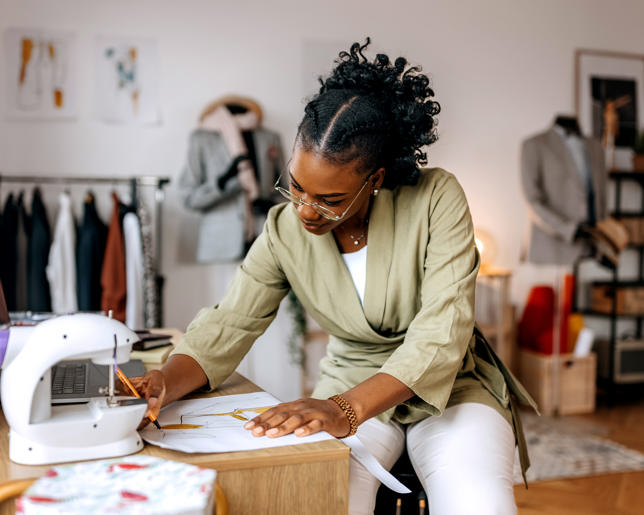 Young well dressed woman designing clothes at her small tailor workshop
