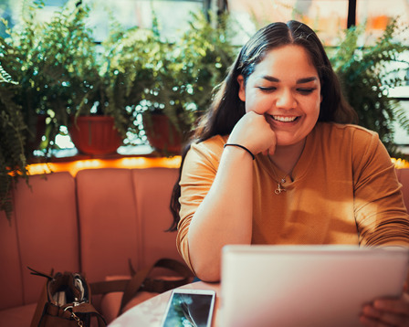 Seated woman using a tablet in a cafe setting