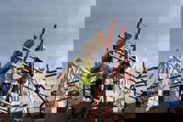 Two construction workers on top of house frame 