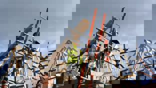 Two construction workers on top of house frame 