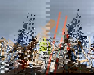 Two construction workers on top of house frame 