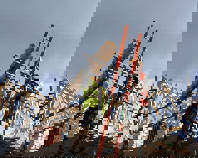 Two construction workers on top of house frame 