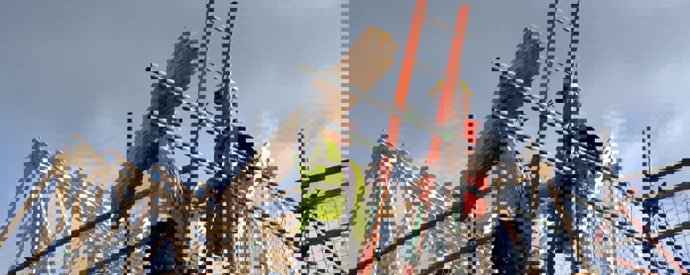 Two construction workers on top of house frame 