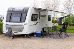Touring caravan parked on caravan site and set up with chairs and leisure equipment