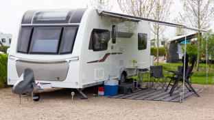 Touring caravan parked on caravan site and set up with chairs and leisure equipment
