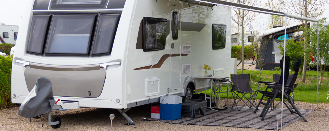 Touring caravan parked on caravan site and set up with chairs and leisure equipment