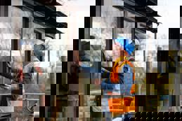 A building manager inspects freshly fitted windows to ensure the sealant is dry and the structure is undamaged.