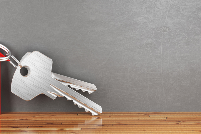 Silver keys attached to a red house-shaped keychain.