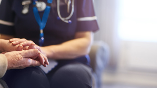 Nurse holding an elderly patient’s hands, offering comfort during a home care visit