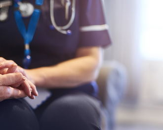 Nurse holding an elderly patient’s hands, offering comfort during a home care visit