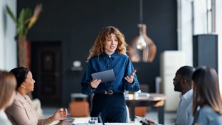 A woman talking to colleagues in a board room