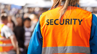 Security staff in orange vest at crowded event.