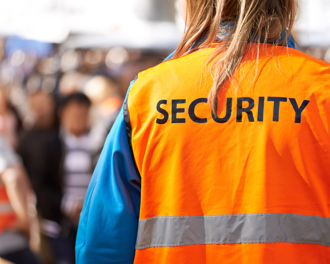 Security staff in orange vest at crowded event.