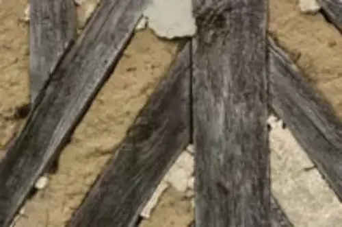 Wooden beams in a crisscross pattern and clay plaster in between.