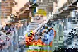 A construction worker carries PVC pipes on his shoulder at a strip mall renovation site.