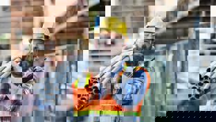 A construction worker carries PVC pipes on his shoulder at a strip mall renovation site.