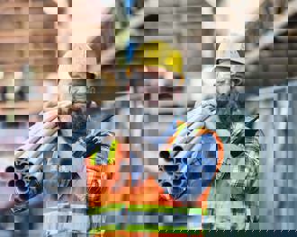 A construction worker carries PVC pipes on his shoulder at a strip mall renovation site.