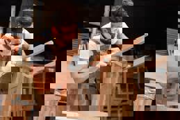 Young carpenter clear scrap wood on the chair in factory