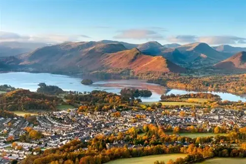  Panoramic view of Keswick beside Derwentwater with autumn trees and the Lake District fells in the background.